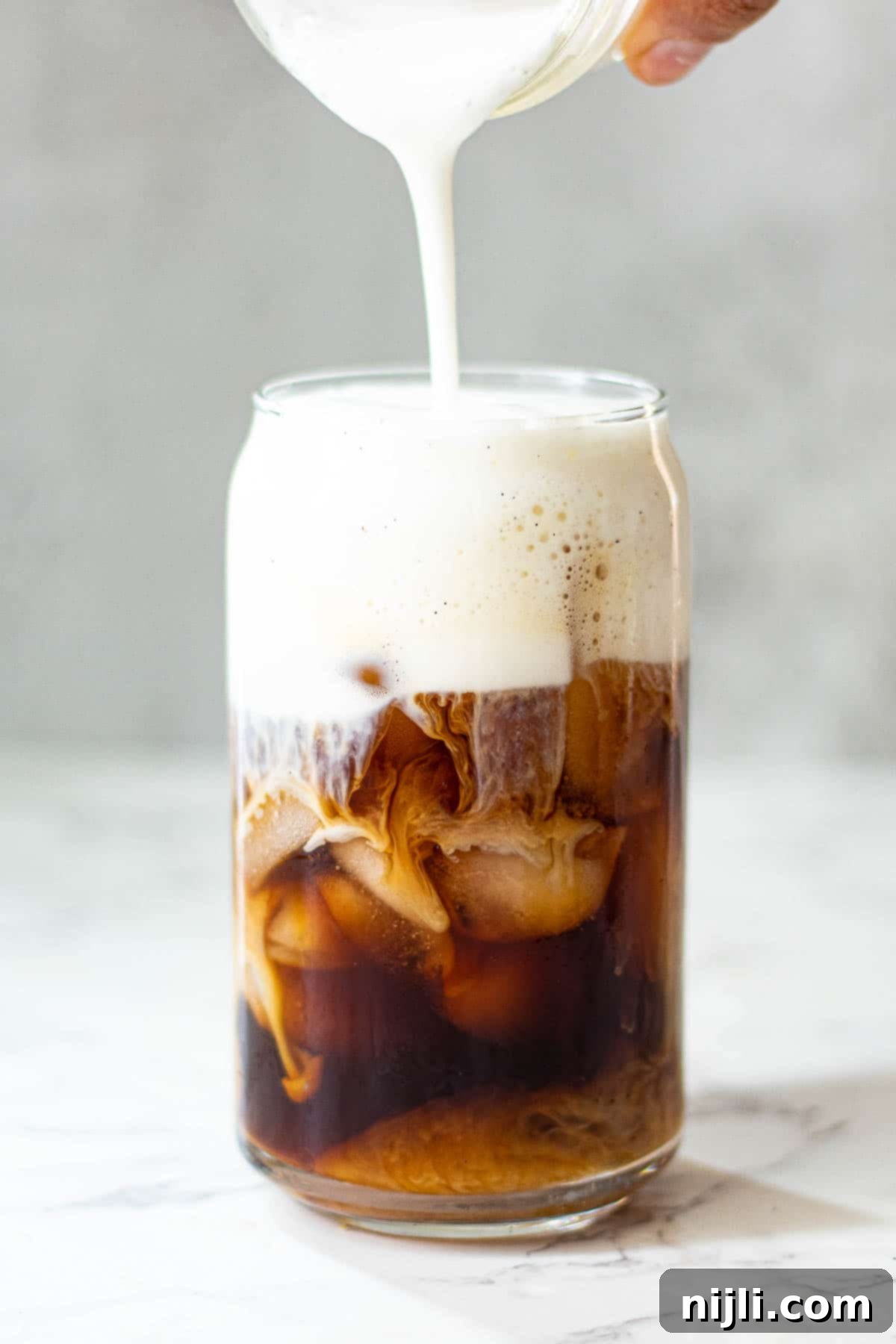 Homemade Sweet Cream Cold Foam 10 Vanilla sweet cream cold foam layered over iced coffee in a clear glass