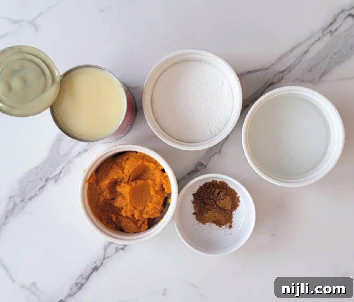 Starbucks Pumpkin Spice Sauce 5 A vibrant flat lay image showcasing all the fresh and canned ingredients needed to make homemade Starbucks pumpkin sauce, including pumpkin puree, condensed milk, spices, sugar, and vanilla.