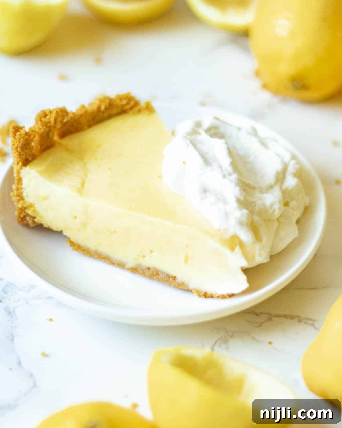 Zesty Lemon Icebox Pie 5 a slice of lemon icebox pie on a plate with whipped cream