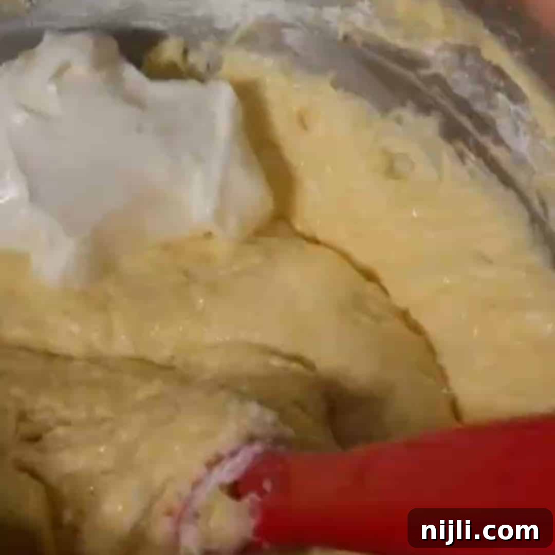 Golden Kentucky Butter Cake with Salted Caramel Glaze 10 the bowl of a stand mixer filled with salted caramel kentucky butter cake batter, with a dollop of sour cream spooned on top