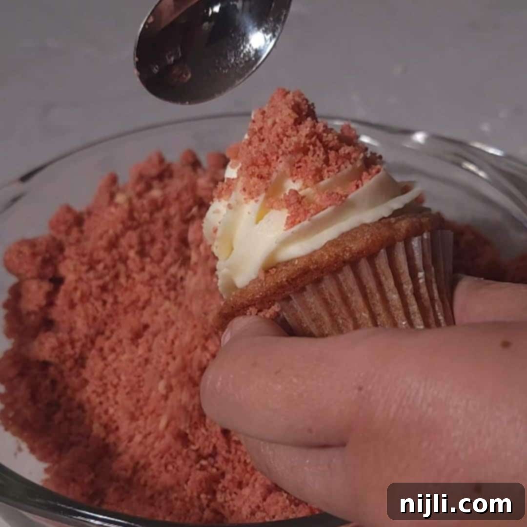Strawberry Crunch Cupcakes 12 Decorating a strawberry crunch cupcake by dipping the frosted top into bright red crumbs for added texture.