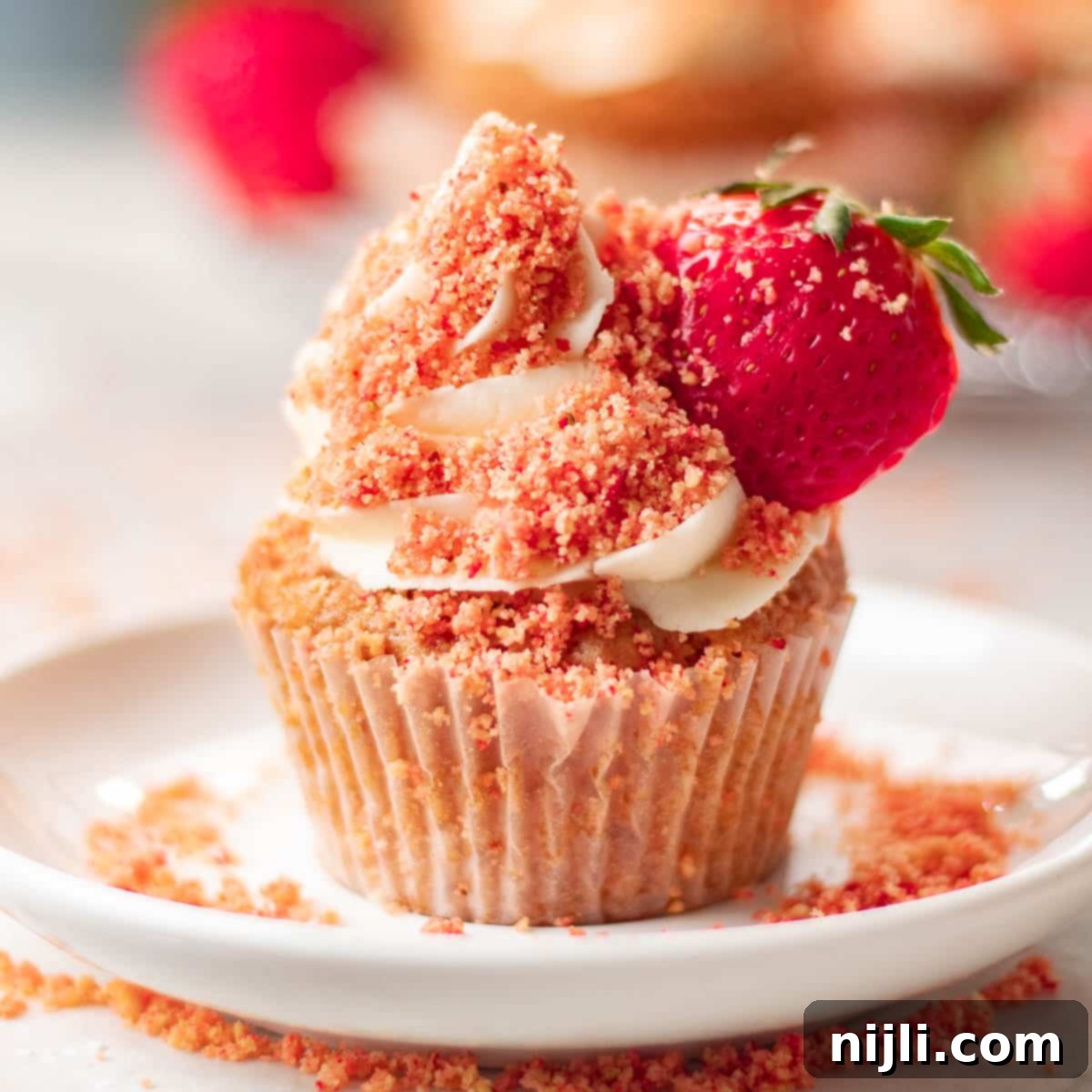 Strawberry Crunch Cupcakes 5 Sumptuous strawberry crunch cupcakes garnished with fresh strawberries and a dusting of crumbs, exuding homemade charm.