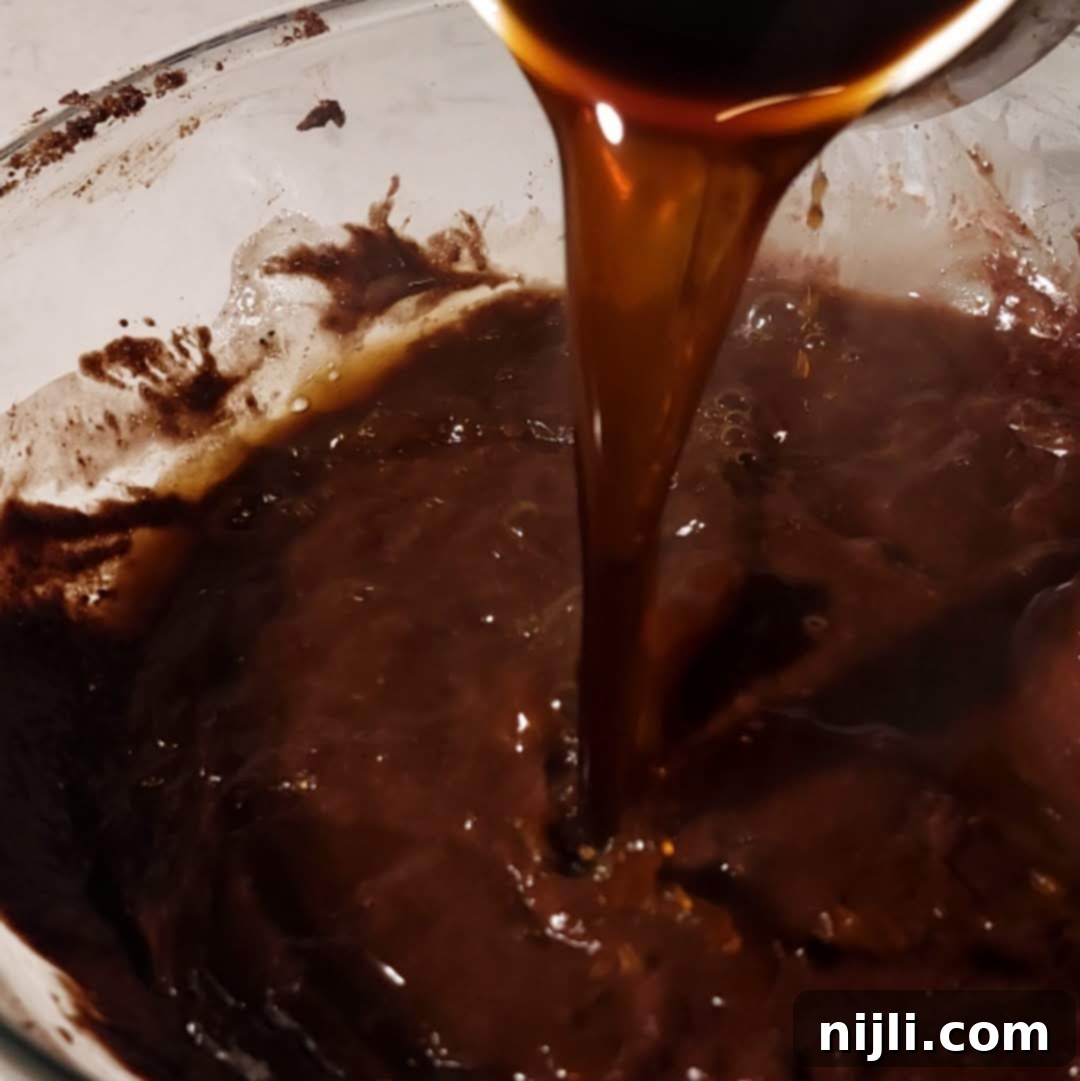 Matilda's Decadent Chocolate Cake 10 The process of gently mixing a dark, luxurious chocolate batter with the final addition of hot coffee, intensifying the flavor for Matilda's Chocolate Cake.