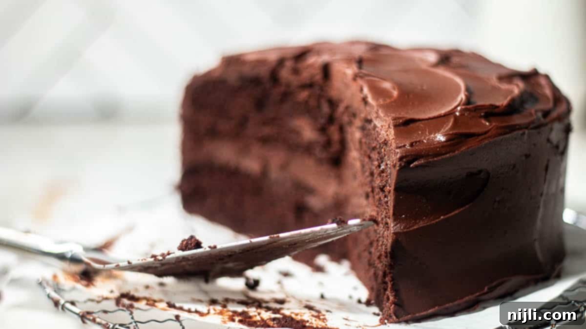 Rich Chocolate Fudge Frosting 4 A decadently frosted chocolate cake with a slice removed, displaying the layers of cake and luxurious chocolate fudge frosting.