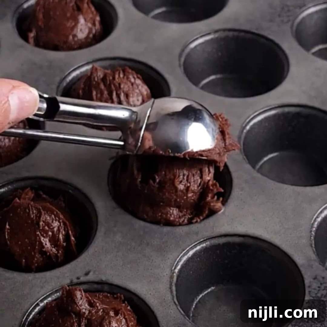 Bite-Sized Brownies 11 Scooping chocolate brownie batter into a muffin tray using an ice cream scoop.