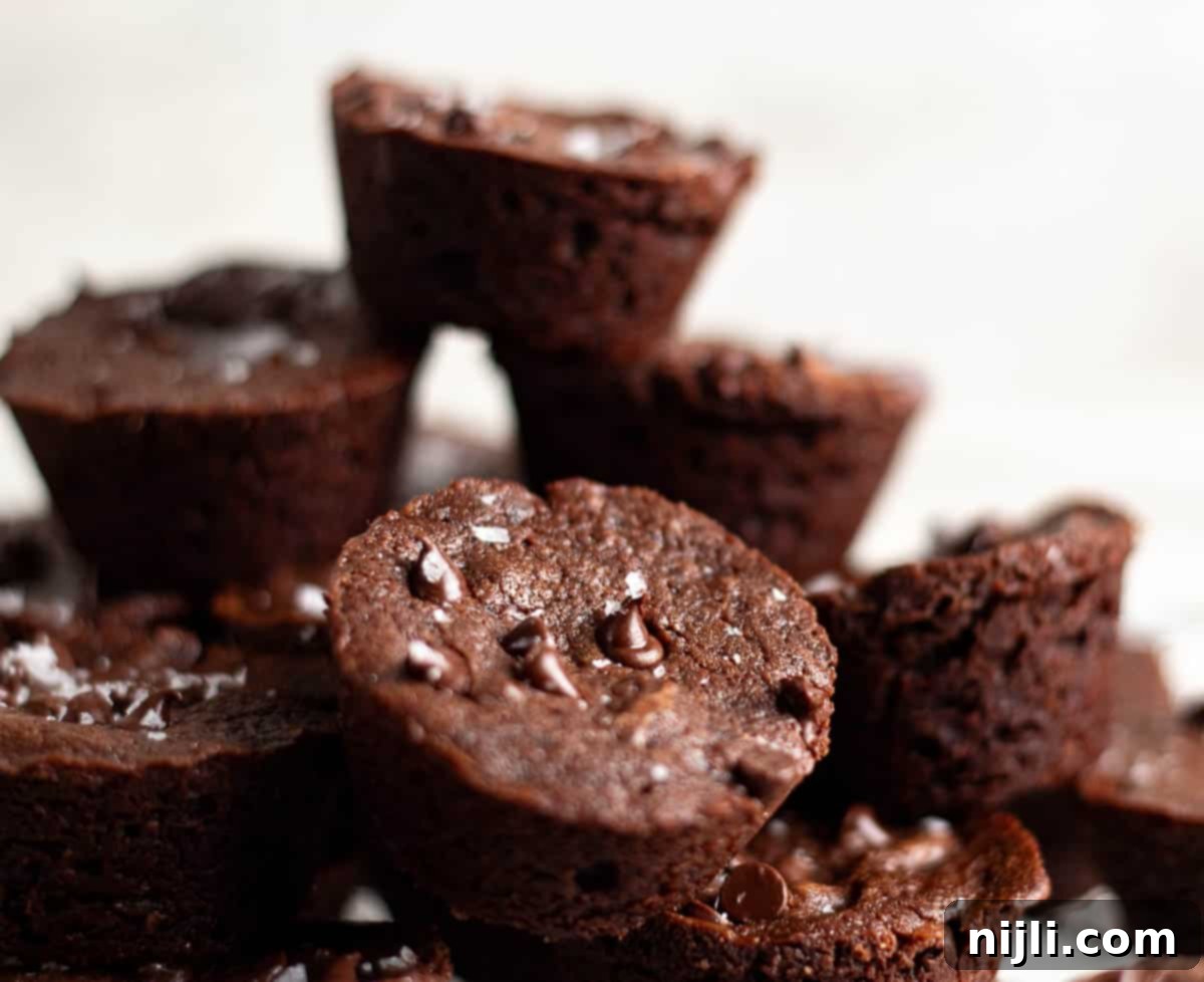 A close-up shot of a pile of 2 bite brownies, topped with sea salt flakes, stacked on a wire rack.