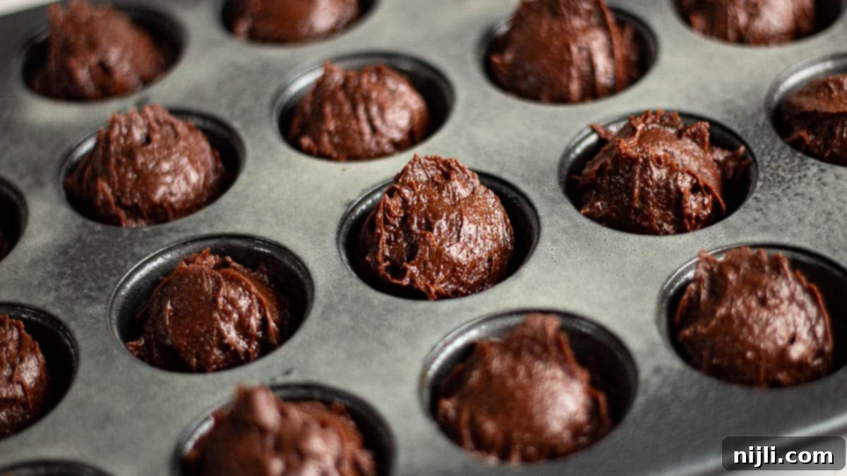 Bite-Sized Brownies 6 A baking tray filled with raw 2 bite brownie batter ready to be baked in mini muffin molds.