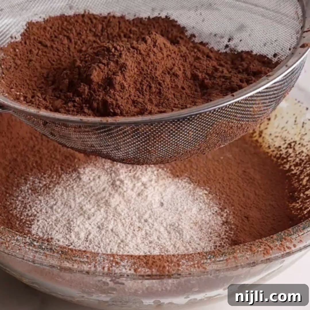 Bite-Sized Brownies 9 Sifting cocoa powder and flour through a metal sieve into a glass mixing bowl.