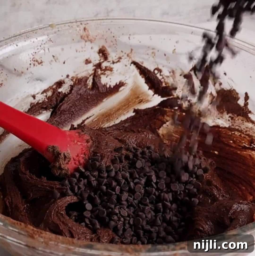 Bite-Sized Brownies 10 Mixing chocolate chips into a bowl of chocolate batter with a red spatula.
