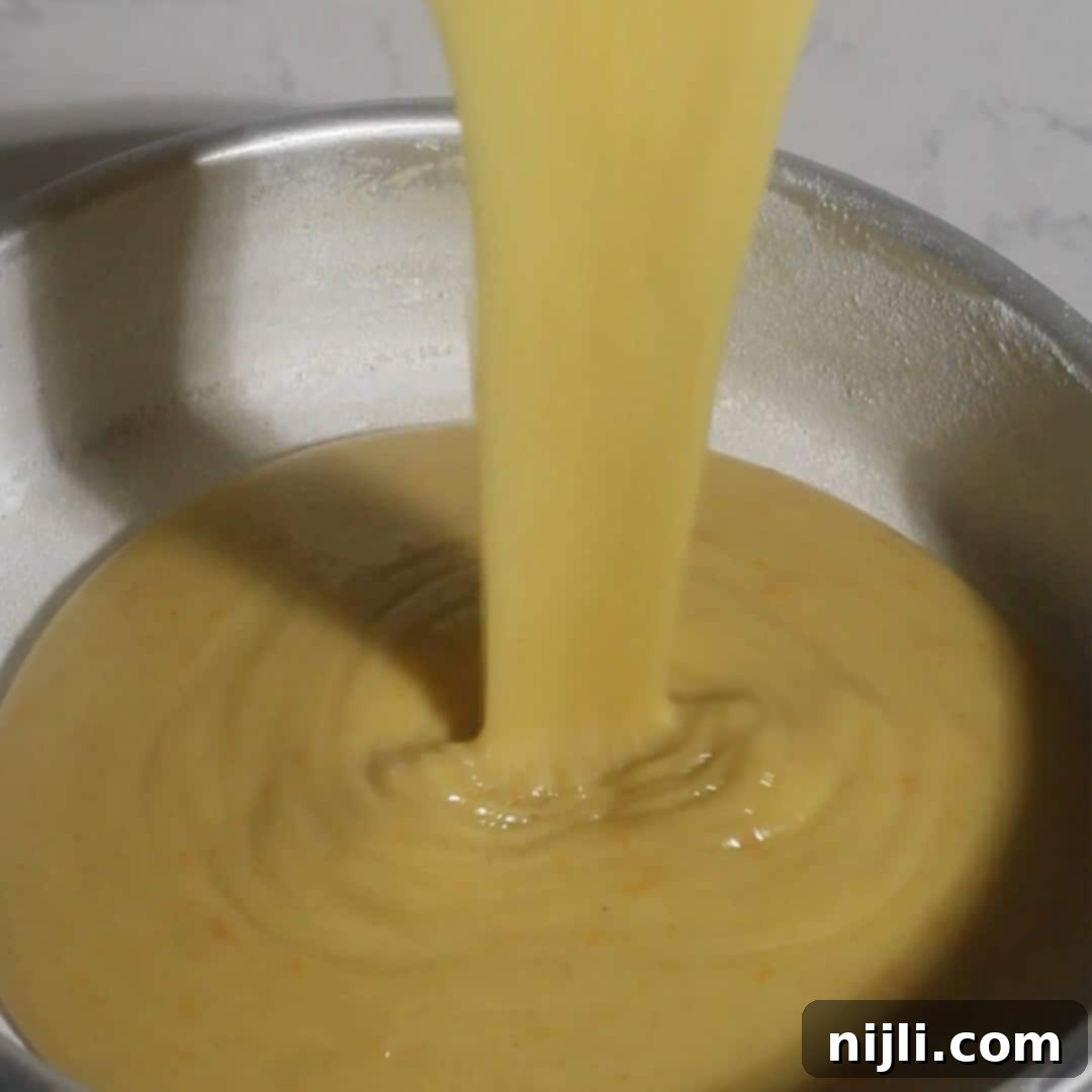 Mediterranean Gluten-Free Olive Oil Cake 11 Pouring the smooth, thick gluten-free olive oil cake batter into a prepared 8-inch round cake pan before baking.