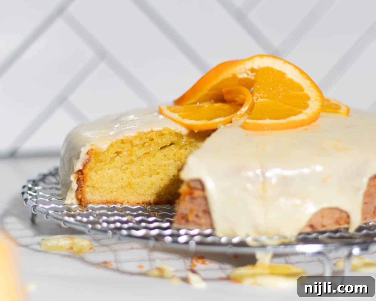 Mediterranean Gluten-Free Olive Oil Cake 5 A decadent gluten-free olive oil cake with a perfect slice removed, topped with a smooth, glossy orange glaze, highlighting its moist interior.