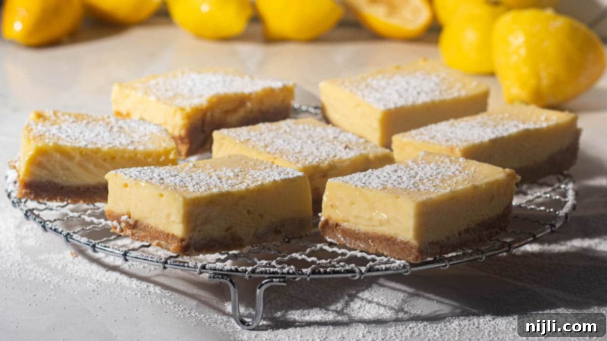 Golden Lemon Delight with Graham Crumb Perfection 4 A side view of lemon bars with graham cracker crusts on a wire rack, showcasing their creamy texture and powdered sugar topping, surrounded by fresh lemons.