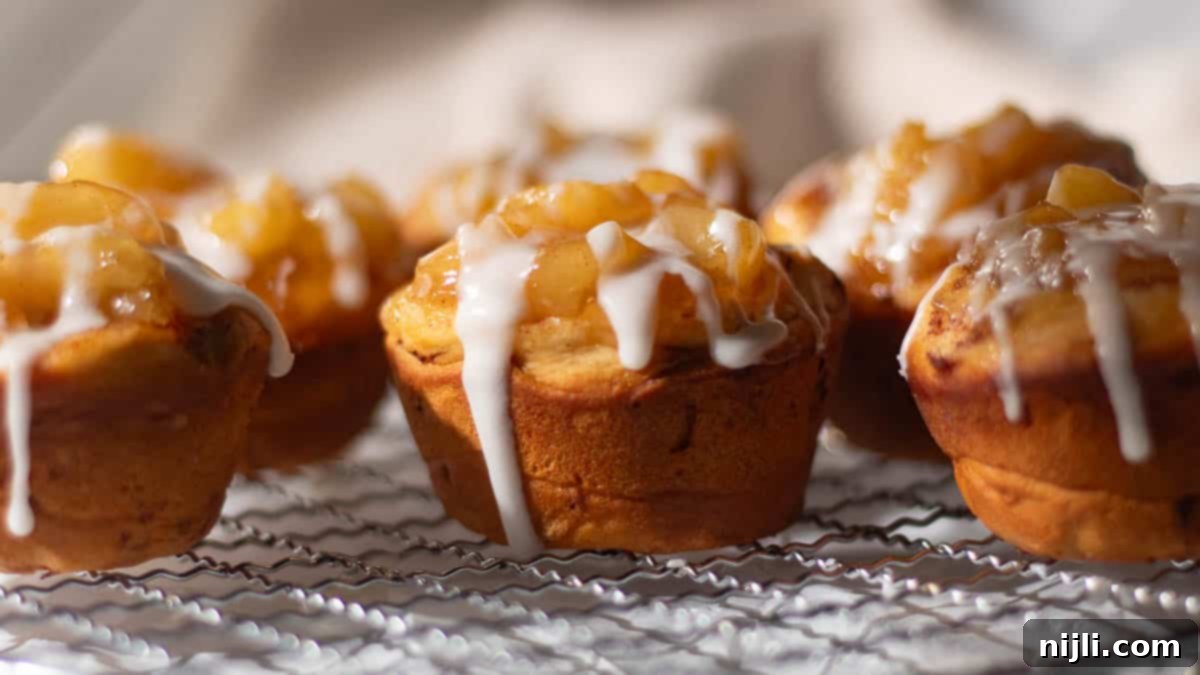 Cinnamon rolls topped with apple pie filling and drizzled with heavy cream icing. The golden rolls are filled with gooey apple pieces.