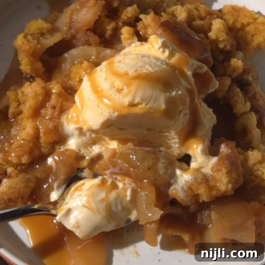 Effortless Cake Mix Apple Cobbler 11 A close-up of freshly baked apple cobbler with yellow cake mix in a baking dish, showing the crisp, golden topping with bubbling caramelized apples underneath.