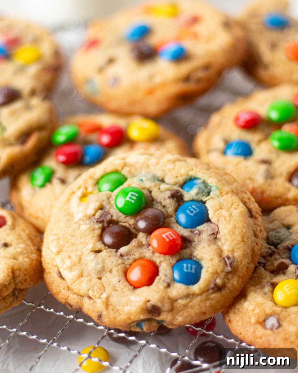 M&M Burst Chocolate Chip Goodness 15 A close-up of M&M chocolate chip cookies with both chocolate chips and colorful M&Ms embedded throughout the thick cookie dough. The image highlights the texture of the cookies, perfect for showcasing a recipe that combines classic chocolate chip cookies with a fun, colorful twist.