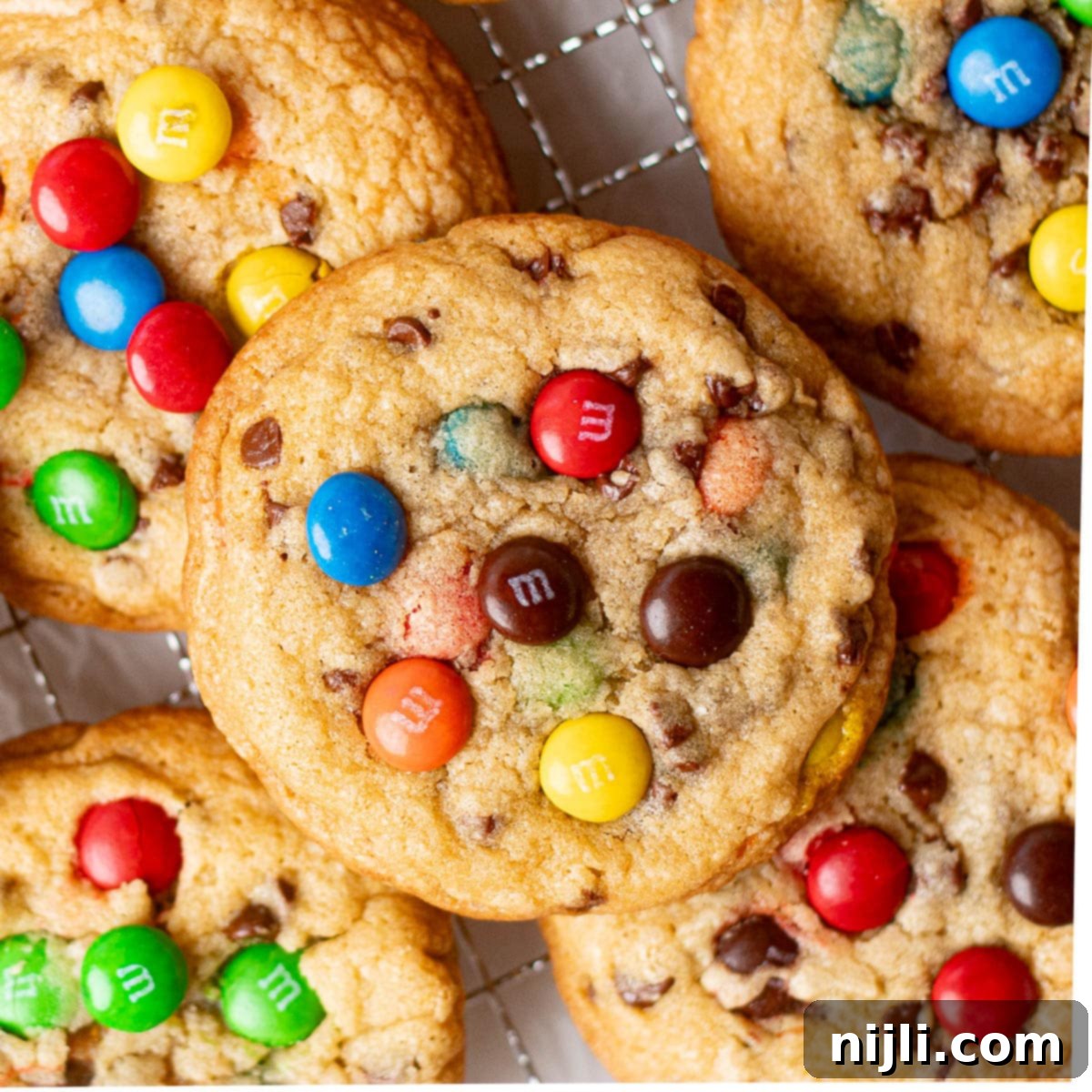 A batch of M&M chocolate chip cookies stacked on a plate, blending colorful M&M candies with semi-sweet chocolate chips for an indulgent, sweet treat. These cookies are perfect for showcasing a recipe that combines the crunch of candy with the richness of chocolate in a soft, chewy cookie.
