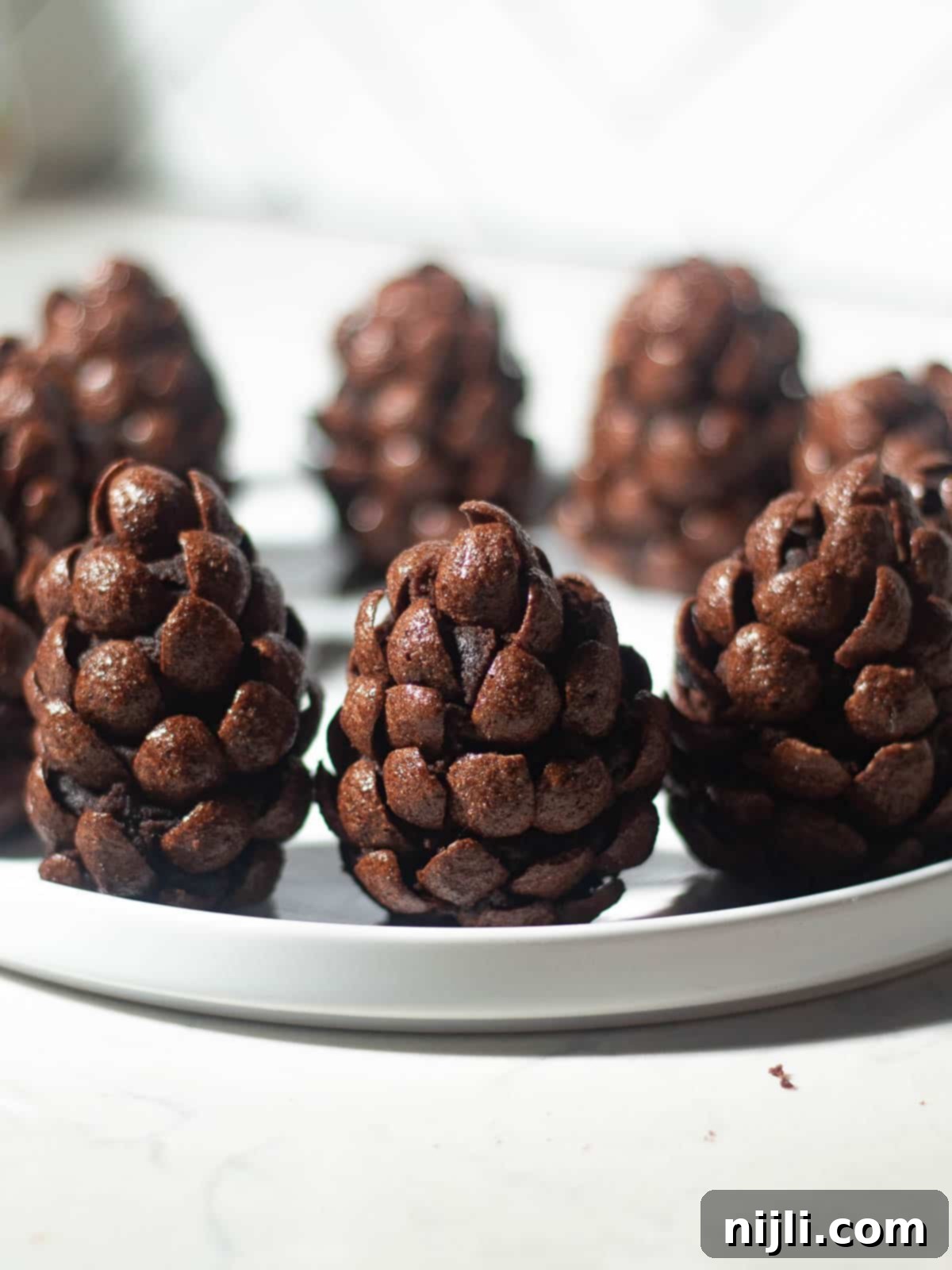 A stacked close-up of three pinecone brownies, each uniquely shaped with chocolate cereal, highlighting the artistry and delicious texture of this holiday treat.