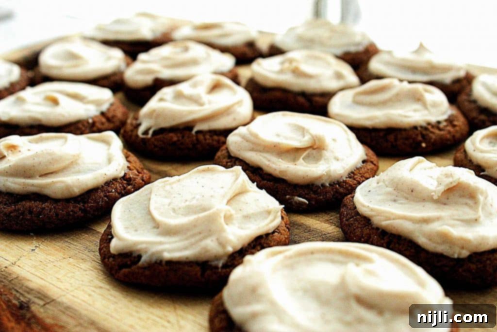 Stout-Infused No-Chill Gingerbread Cookies with Brown Butter Cream Cheese Frosting 3 Close-up of a stack of stout gingerbread molasses cookies, showcasing their soft, chewy interior and the rustic sugar coating, with one cookie broken in half to reveal its tender crumb.