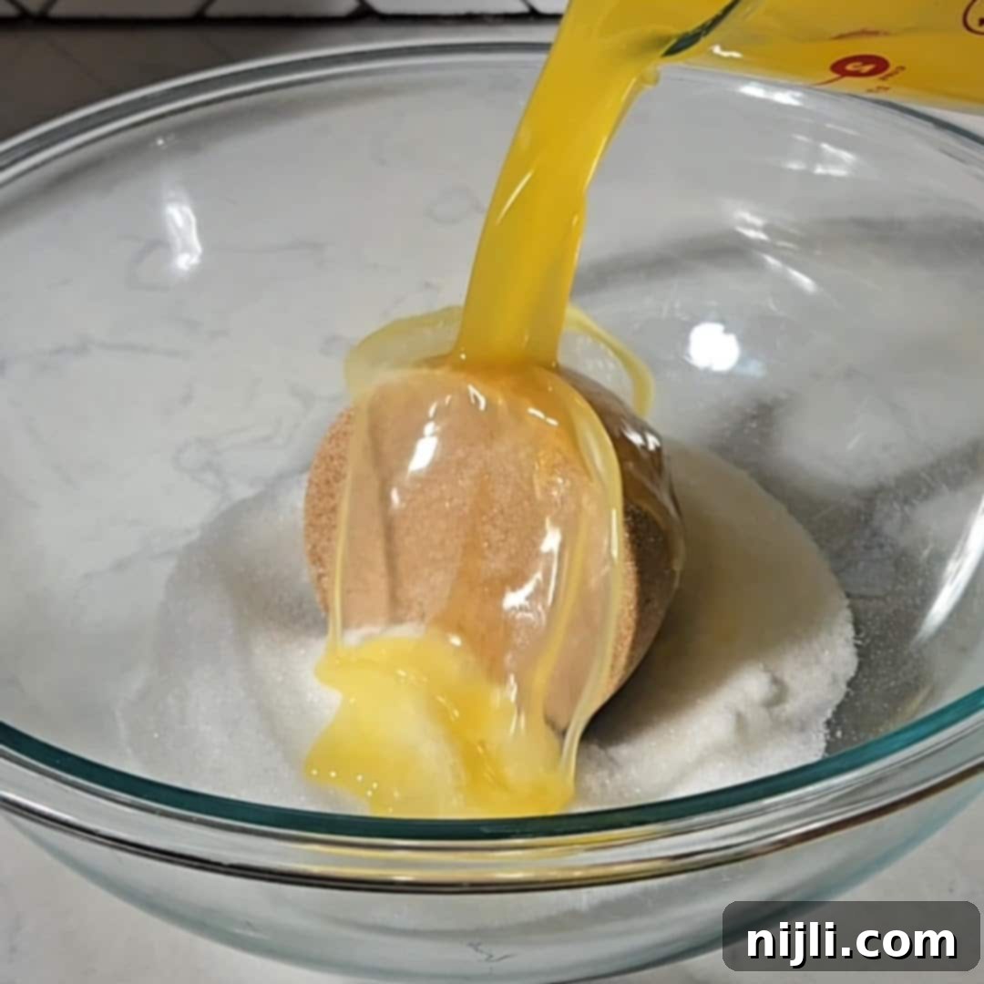 Melted butter being poured over a mixture of sugar and brown sugar in a glass mixing bowl, creating the foundation for fudgy brownies with cream cheese frosting. The process highlights an easy dessert recipe.