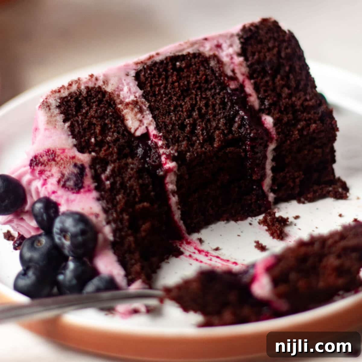 Chocolate Blueberry Delight 4 Sliced chocolate blueberry cake with layers of moist chocolate sponge, blueberry jam filling, and whipped berry buttercream.