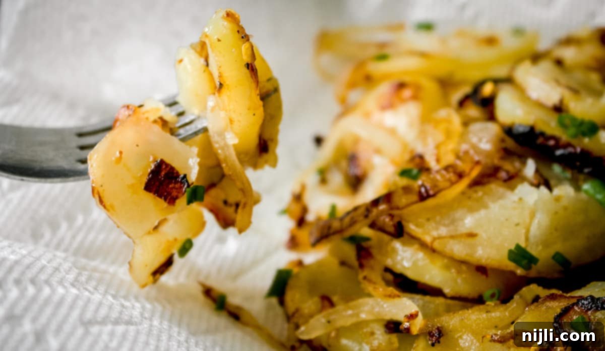 Skillet Potatoes and Onions 3 a fork scooping some fried potatoes and onions
