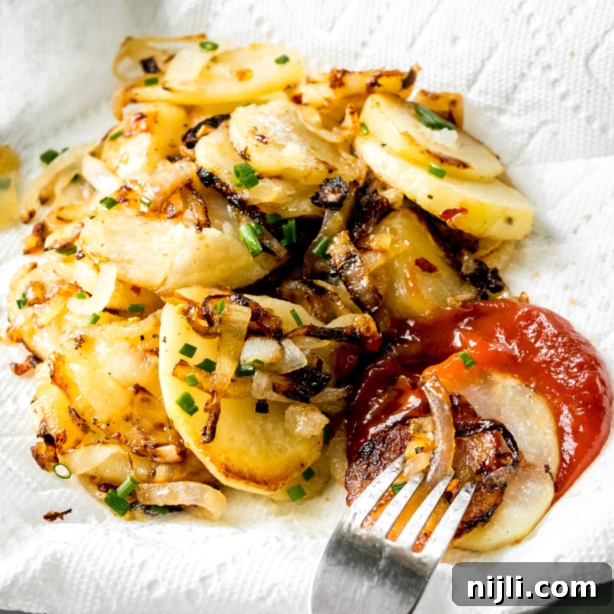 Skillet Potatoes and Onions 6 Fried Potatoes and Onions on a plate with a paper towel and ketchup
