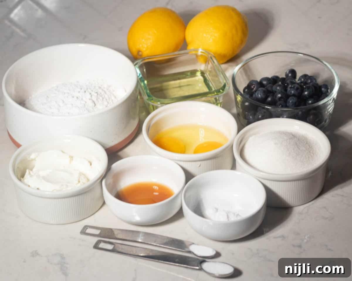 Sunny Lemon Blueberry Mascarpone Delight 4 Overhead view of dry and wet ingredients for lemon blueberry mascarpone cake, including flour, eggs, sugar, oil, blueberries, lemons, mascarpone cheese, baking powder, baking soda, salt, and vanilla extract.
