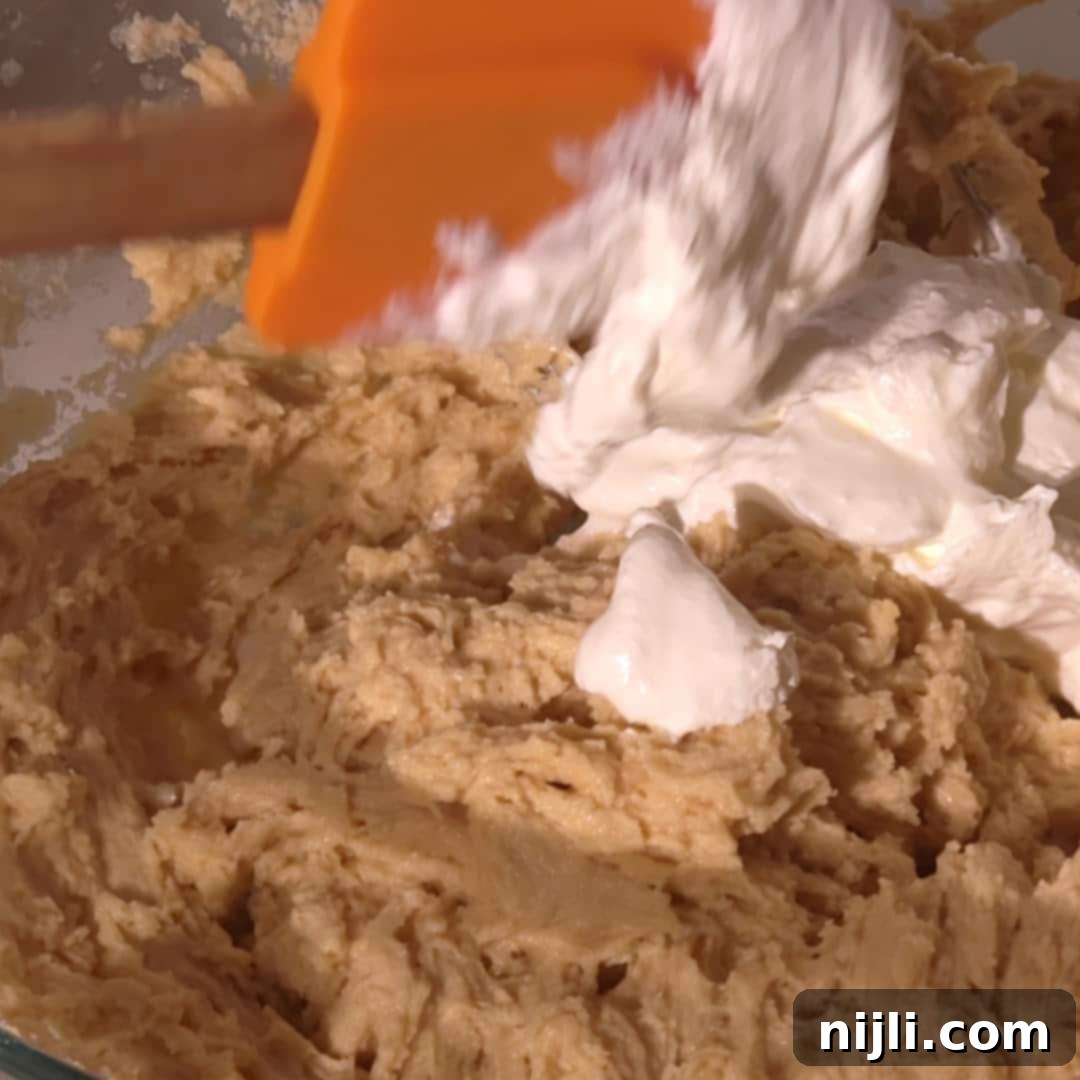 Homemade Blackberry Coffee Cake 11 A dollop of sour cream is folded into thick blackberry coffee cake batter with an orange spatula, adding creamy richness and moisture.