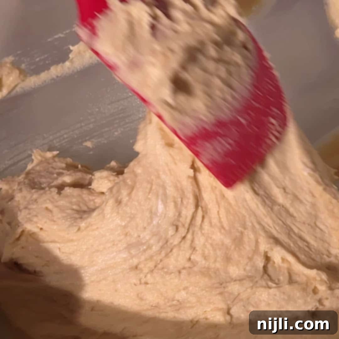 Homemade Blackberry Coffee Cake 12 A red spatula folds thick, creamy batter in a bowl while preparing blackberry coffee cake.