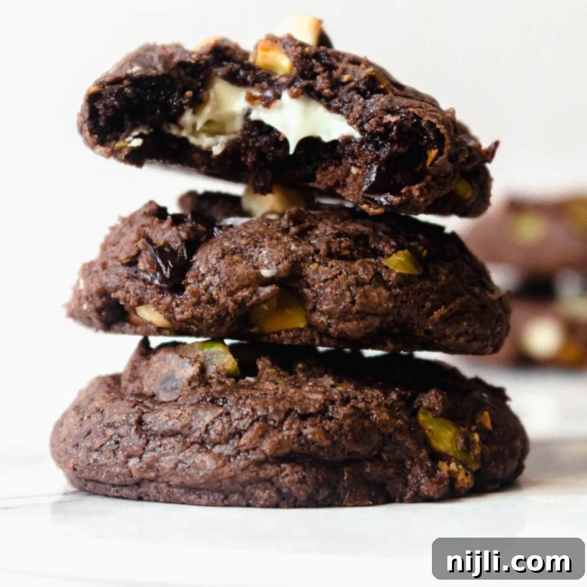 Decadent White Chocolate Cherry Pistachio Brownie Cookies 7 stacked brownie mix cookies with a bite taken out