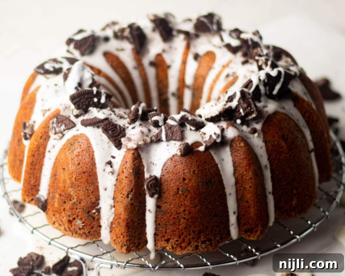 Decadent Oreo Pound Cake 6 Whole Oreo pound cake resting on a wire rack, topped with white glaze and generous pieces of crushed Oreo cookies.