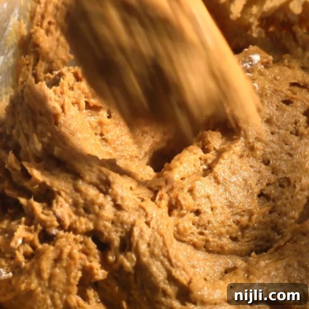 Spiced Pumpkin Perfection 12 Thick pumpkin spice donut batter being stirred, highlighting the rich, spiced texture of the mixture.