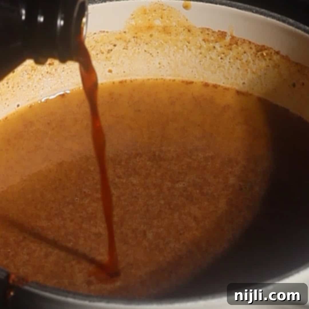 Starbucks Style Pumpkin Cold Foam 8 Vanilla extract being poured into a saucepan of pumpkin cold foam mixture while cooking.