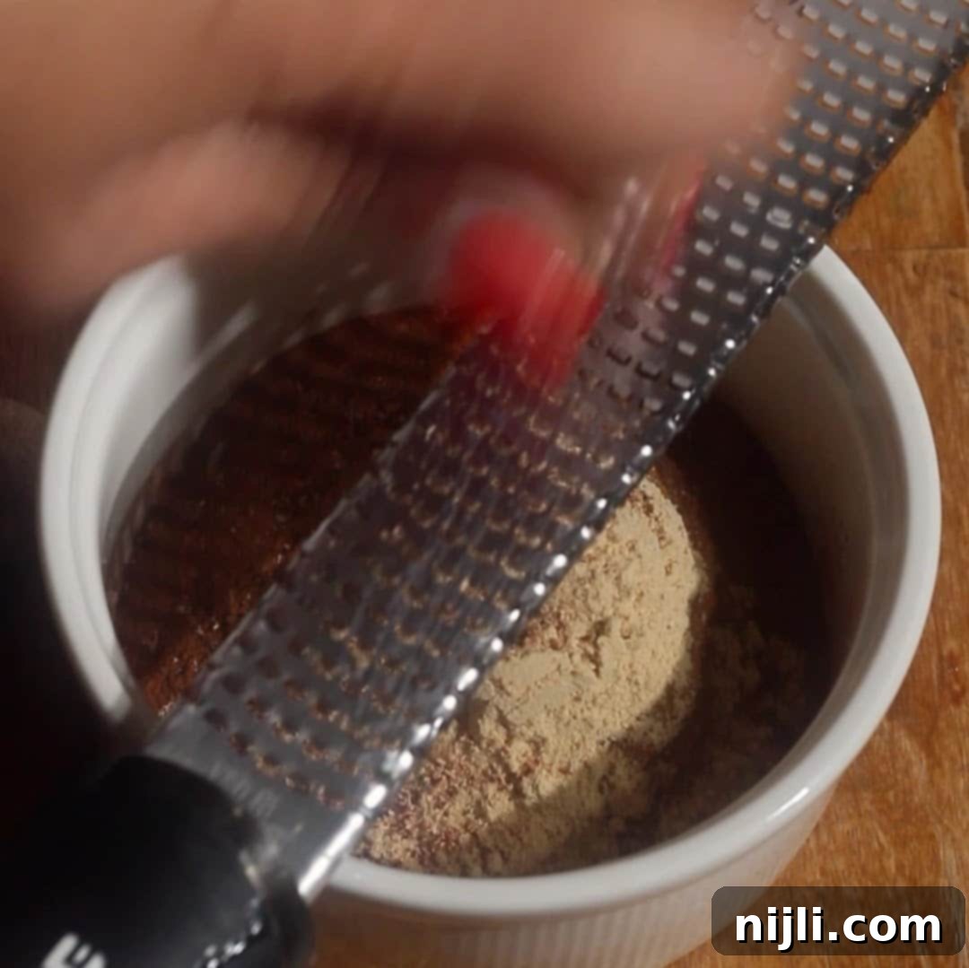 Spiced Pumpkin Harmony 7 Hand grating whole nutmeg into a bowl with other spices for homemade pumpkin spice blend.