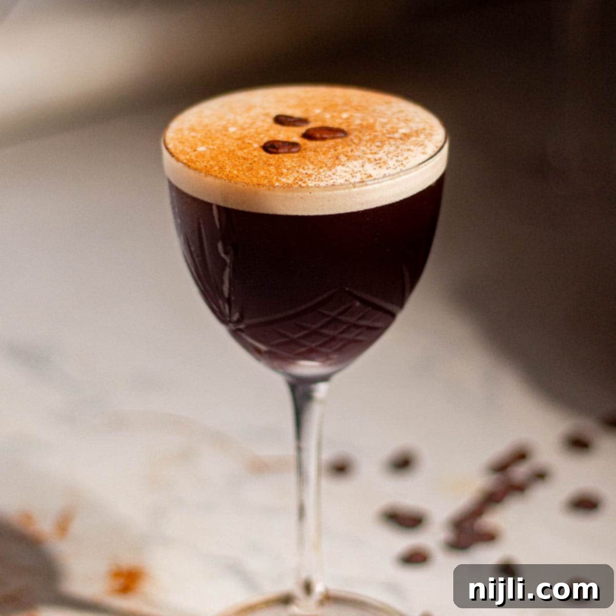 Classic rum espresso martini topped with coffee beans and dusted crema, photographed in elegant glassware.
