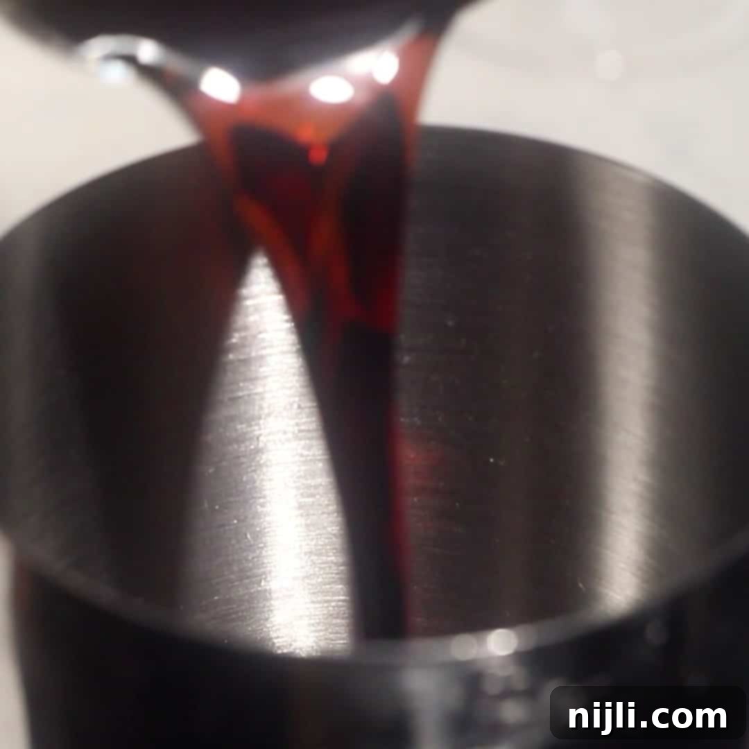 Pouring dark rum into a cocktail shaker to make a spiced rum espresso martini.