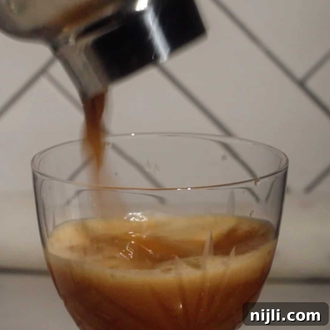 Pouring shaken espresso cocktail into a glass for a rum espresso martini.