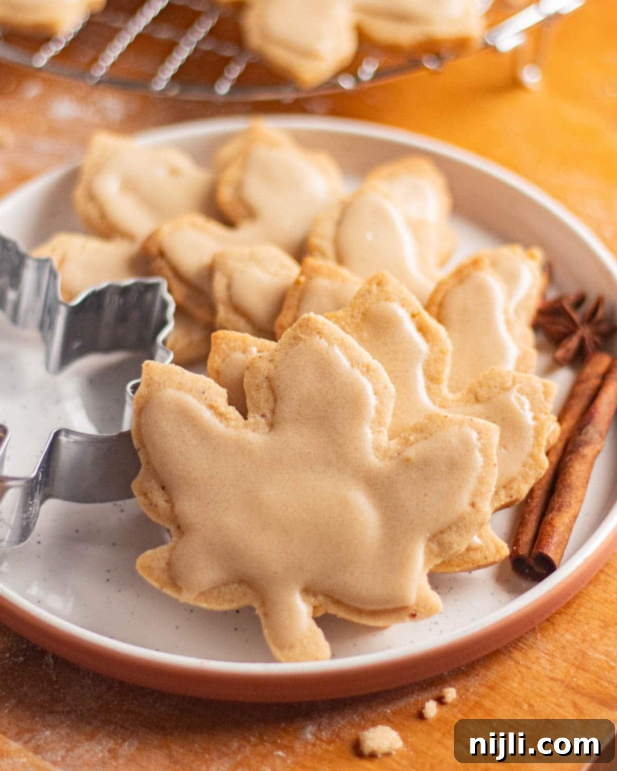 Brown Butter Bliss Cookies 3 Maple leaf cutout brown butter sugar cookies cooling on a wire rack with icing set on top.