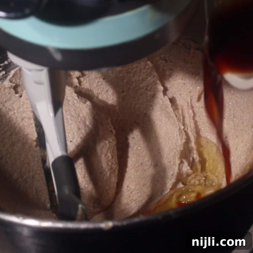 Brown Butter Bliss Cookies 8 anilla extract being poured into whipped brown butter sugar cookie dough.
