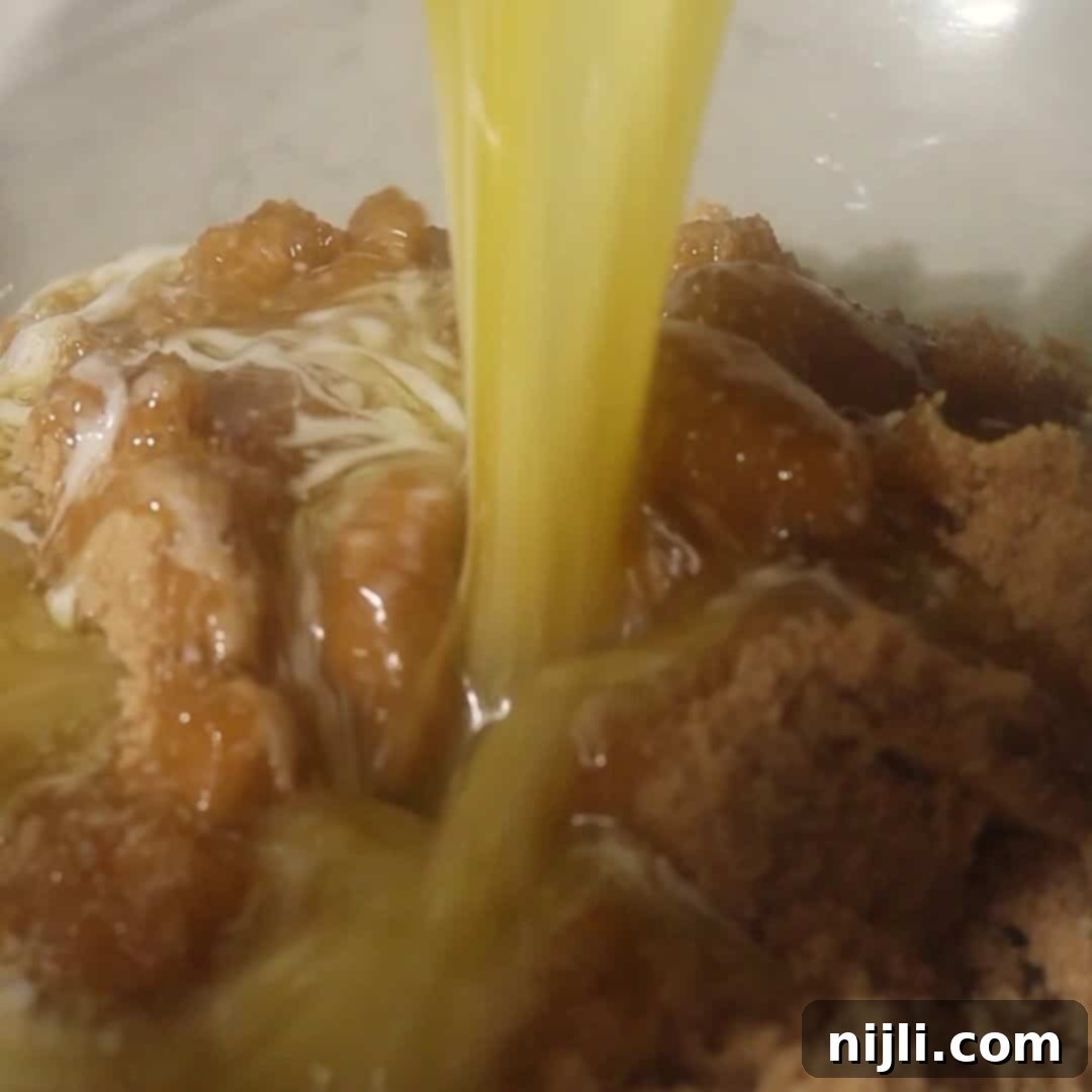 The Everything Cookie 7 Stream of melted butter poured over packed brown sugar to begin kitchen sink cookie dough.
