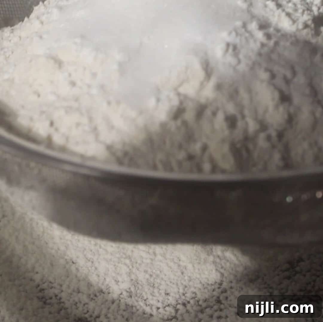 The Everything Cookie 9 Flour mixture being sifted together to prepare dough for kitchen sink cookies.