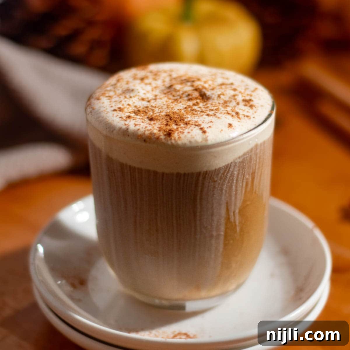 Homemade pumpkin cold foam recipe served over iced coffee with a creamy cinnamon-spiced topping.