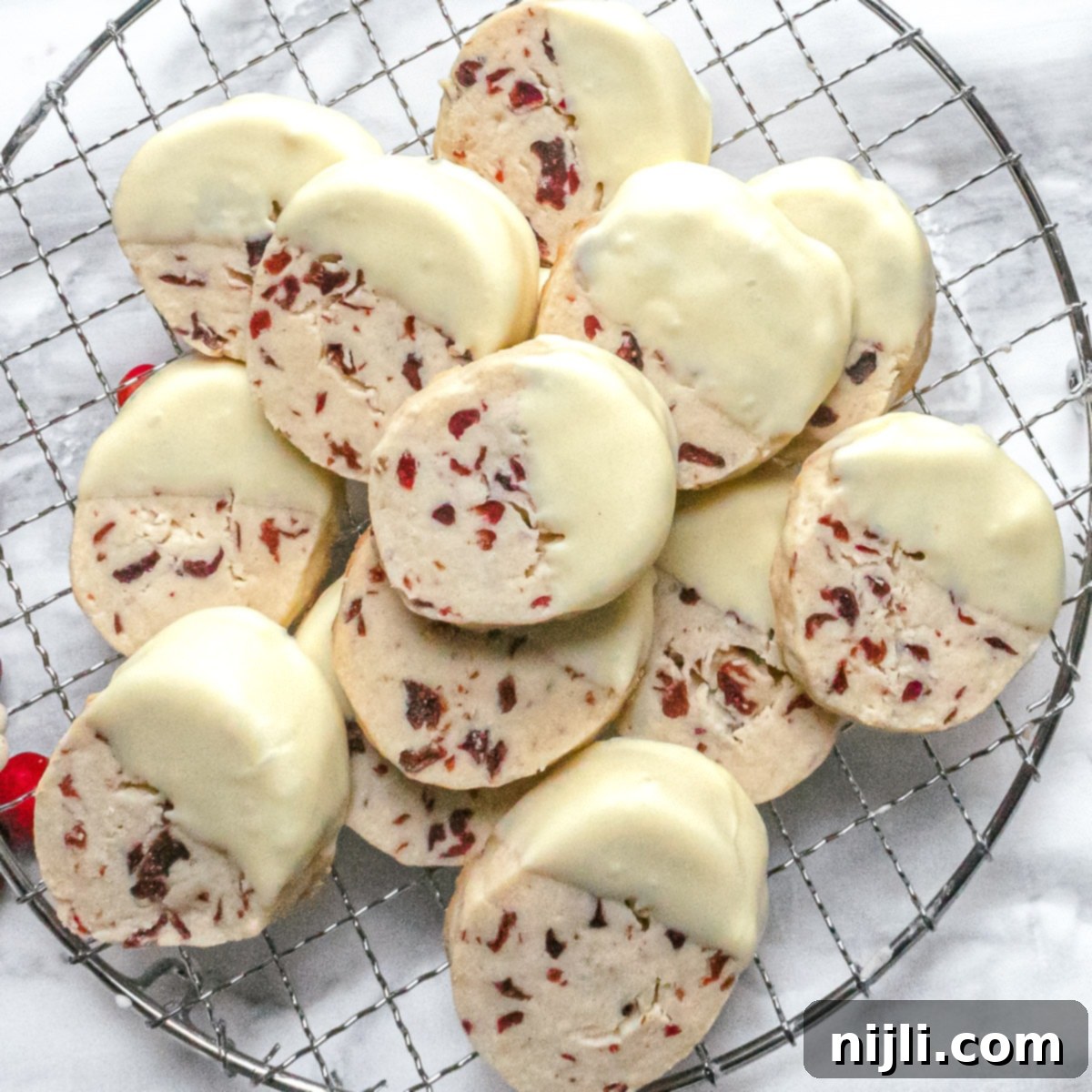 Cranberry White Chocolate Shortbread Delights 2 Cranberry white chocolate shortbread cookies on a rack, perfectly baked and ready to enjoy.