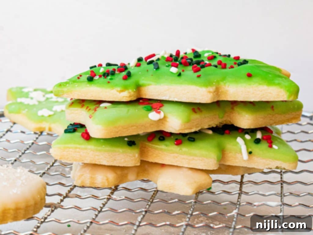 Perfectly Shaped Sugar Cookies 7 Stack of decorated sugar cookies on a wire rack with sprinkles scattered around