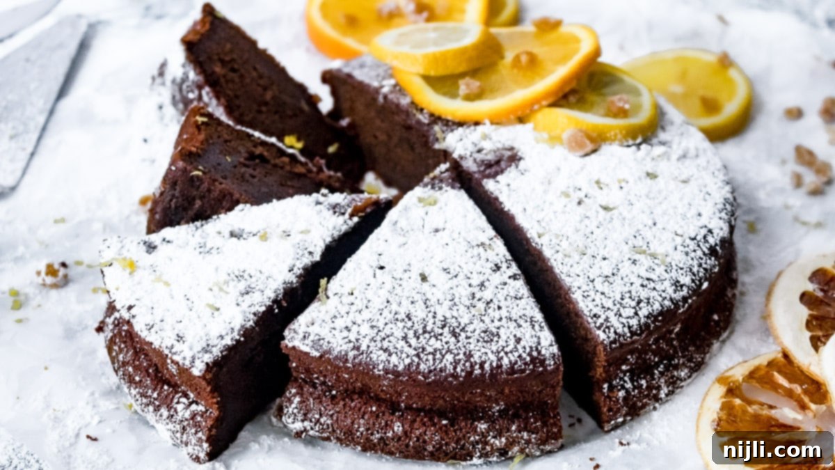 Sliced chocolate olive oil cake garnished with citrus and crystallized ginger, emphasizing its fresh ingredients.