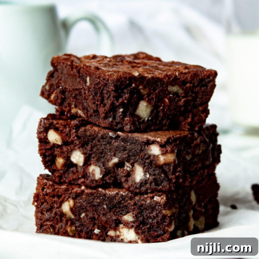 Gooey Chocolate Walnut Brownies 3 stack of dark chocolate walnut brownies on a counter.