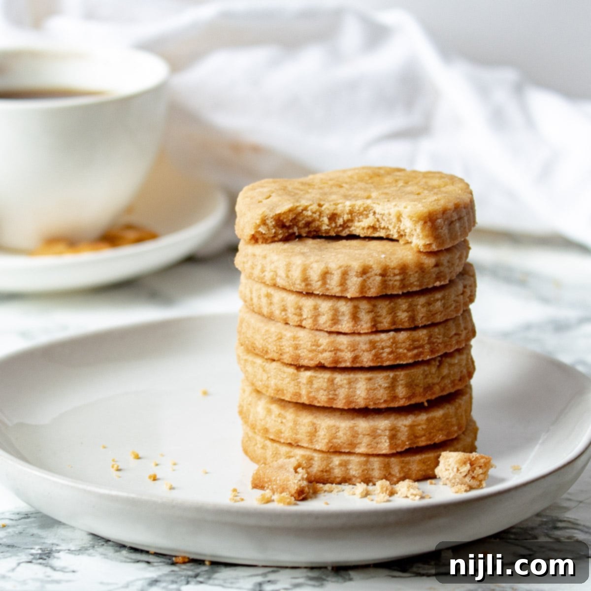 Golden Brown Shortbread Perfection 2 stack of brown sugar shortbread cookies with a cup of coffee in the background