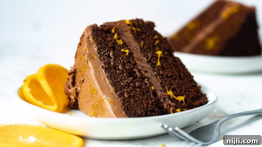 Zesty Chocolate Orange Sensation 5 moist chocolate orange cake on a plate with a fork and another slice of cake in the background