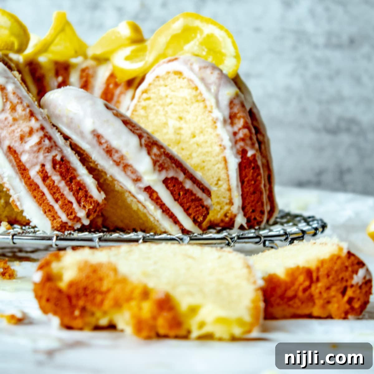 Sunshine Lemon Sour Cream Cake 2 lemon sour cream pound cake with a rich, buttery lemon glaze dripping down its sides, sliced on a white cake stand