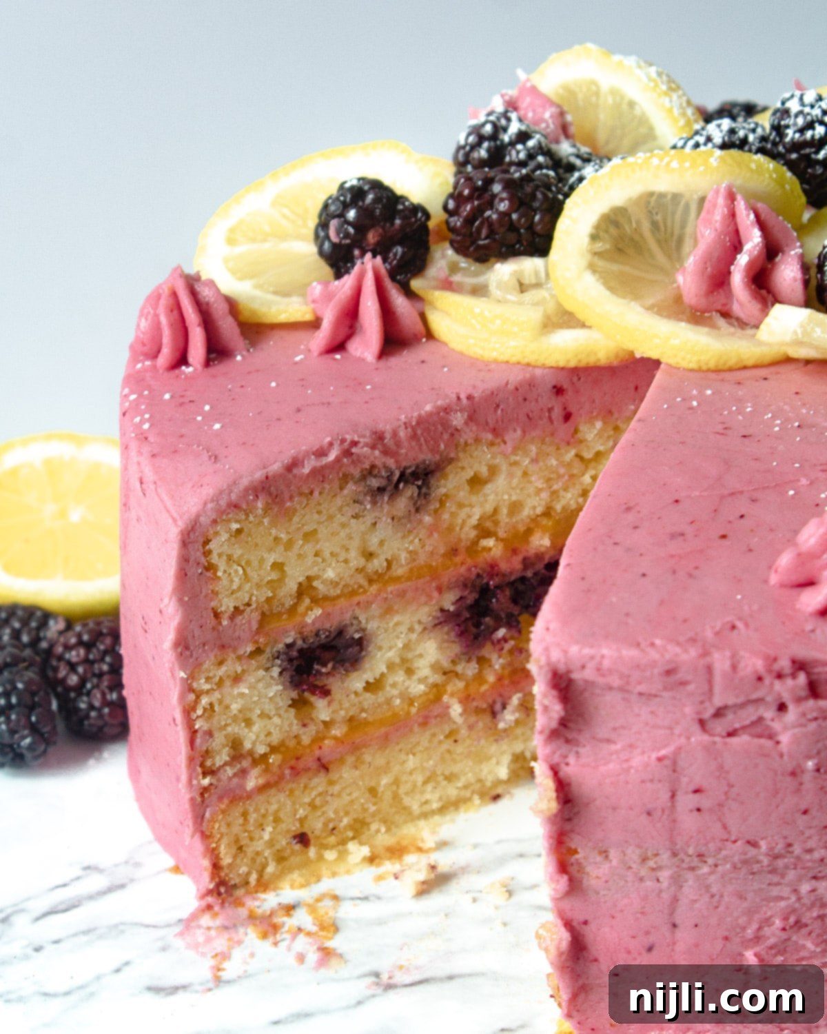 Sunshine Lemon Blackberry Delight 5 A glorious lemon cake with blackberry filling, partially sliced, on an elegant cake stand.